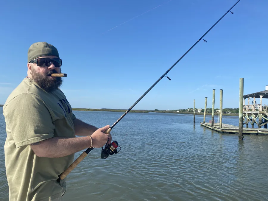 An angler casting from a dock over the marsh at Murrells Inlet on a bright day