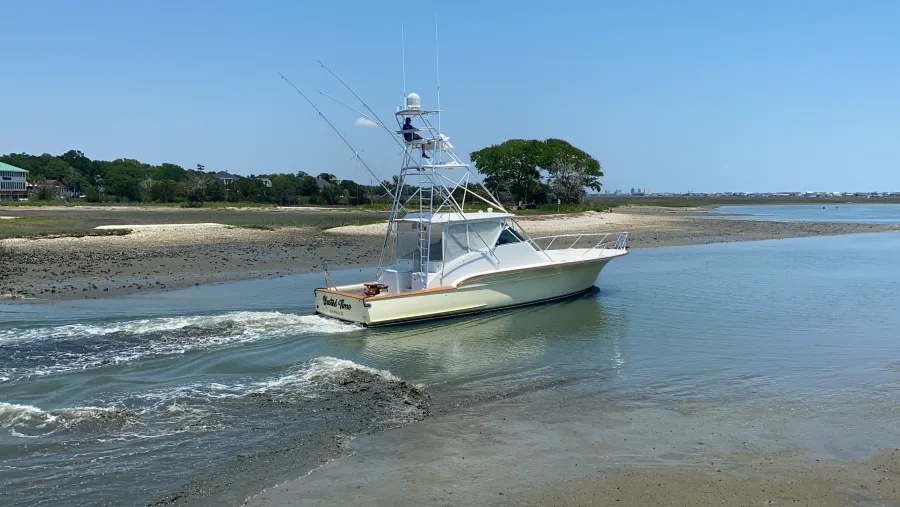 A sportfishing boat running out past the beach at the mouth of Murrells Inlet